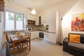 Uma cozinha moderna com armários brancos, uma mesa de jantar com cadeiras e um sofá na sala de estar.