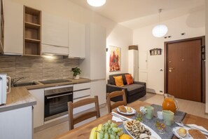 A modern kitchen with a dining area, a wooden cabinet, a sink, and a table set with food and drinks. - STRAMBIO, 8 – Smart Stay in Milan (Milano)