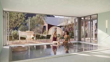 A modern indoor swimming pool with glass walls, a person sitting by the pool, and outdoor seating.