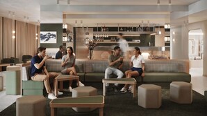 Un área de descanso moderna con diferentes disposiciones de asientos, una zona de bar con botellas y una obra de arte colgada en la pared.