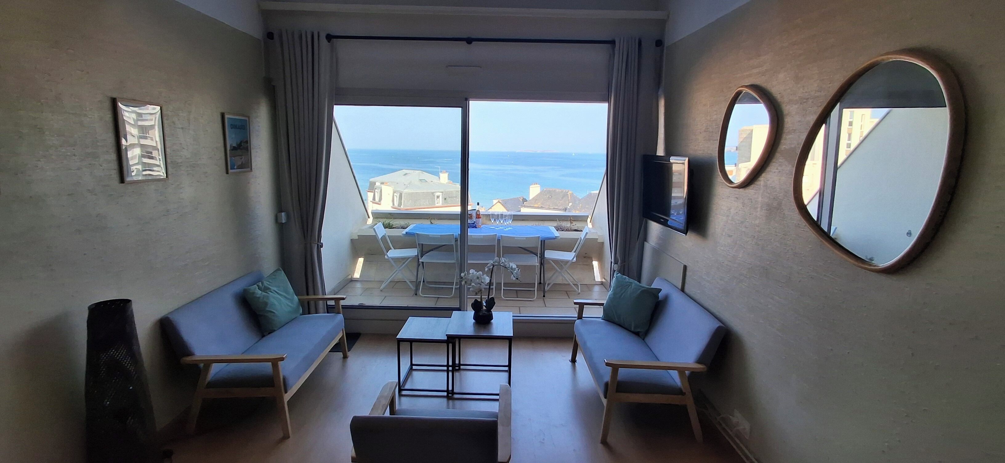Una habitación con sofá, una mesita, televisor y vista al mar.