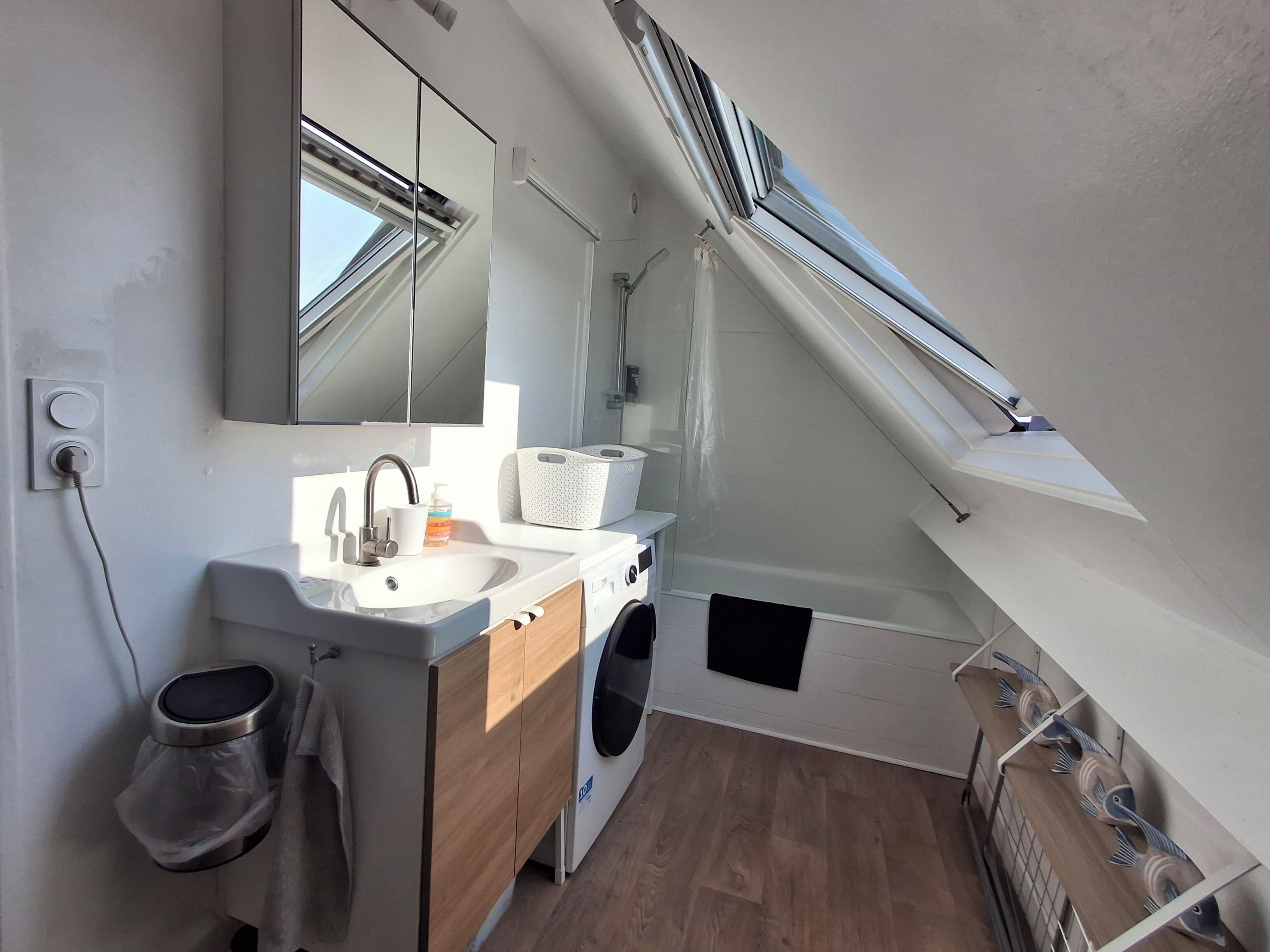 A modern bathroom with a sink, mirror, and a washing machine.