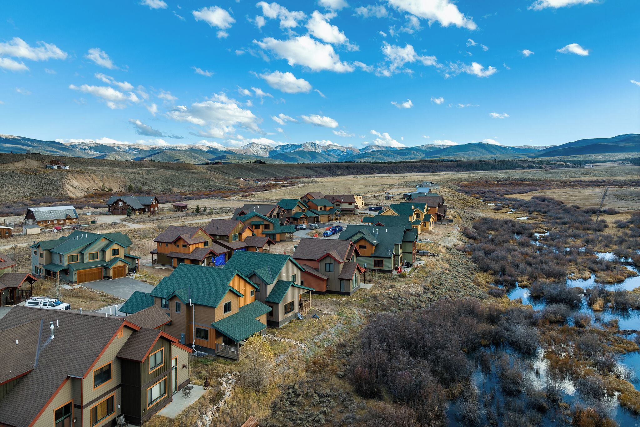 A residential area with houses featuring green roofs and a mountainous backdrop.
