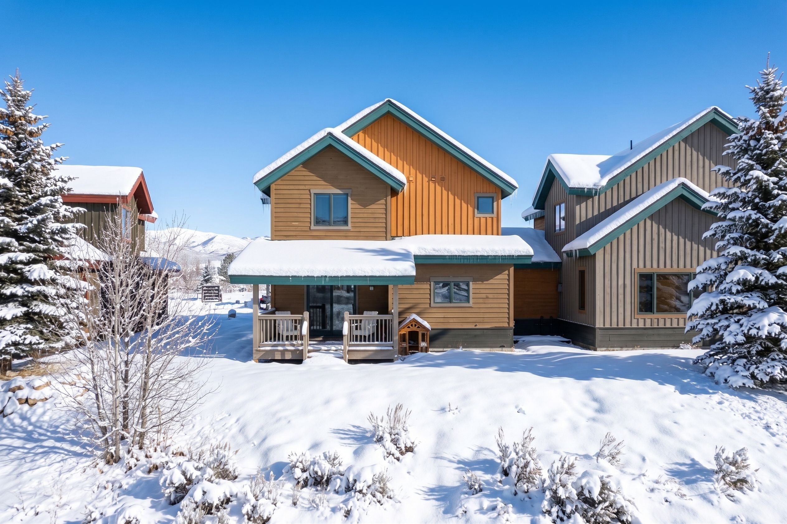 Un chalet en bois doté d’un porche couvert et d’une petite structure ressemblant à une cabane.
