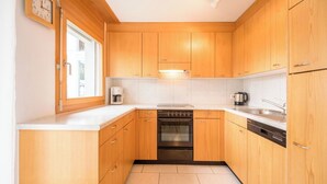 Una cocina compacta con armarios de madera, horno empotrado y lavavajillas.