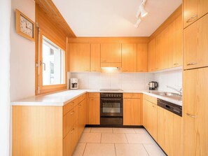 Eine kleine Küche mit Holzausstattung, einem eingebauten Backofen und einem Geschirrspüler.