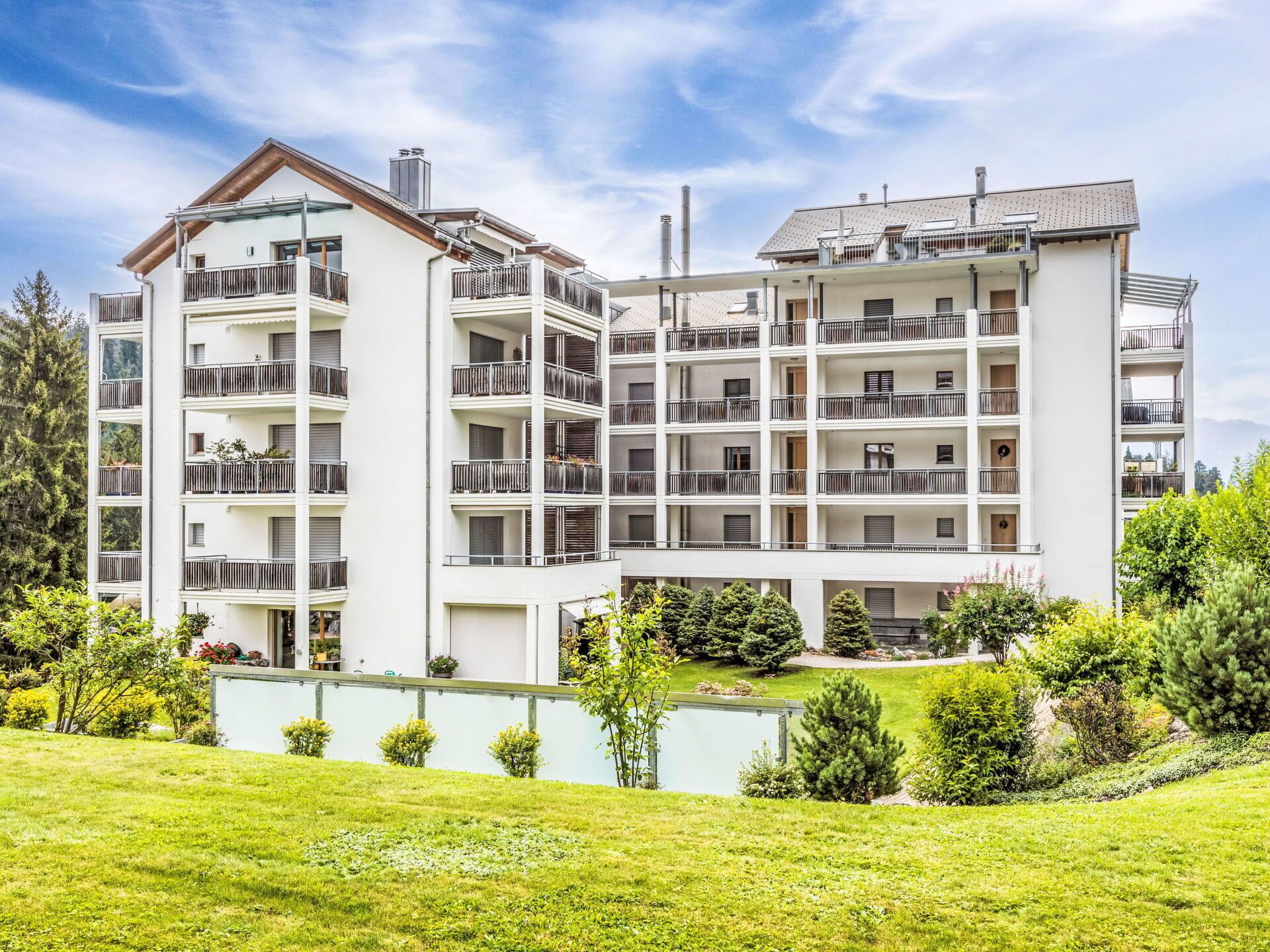 A multi-story hotel with balconies, a pool, and a well-maintained garden.