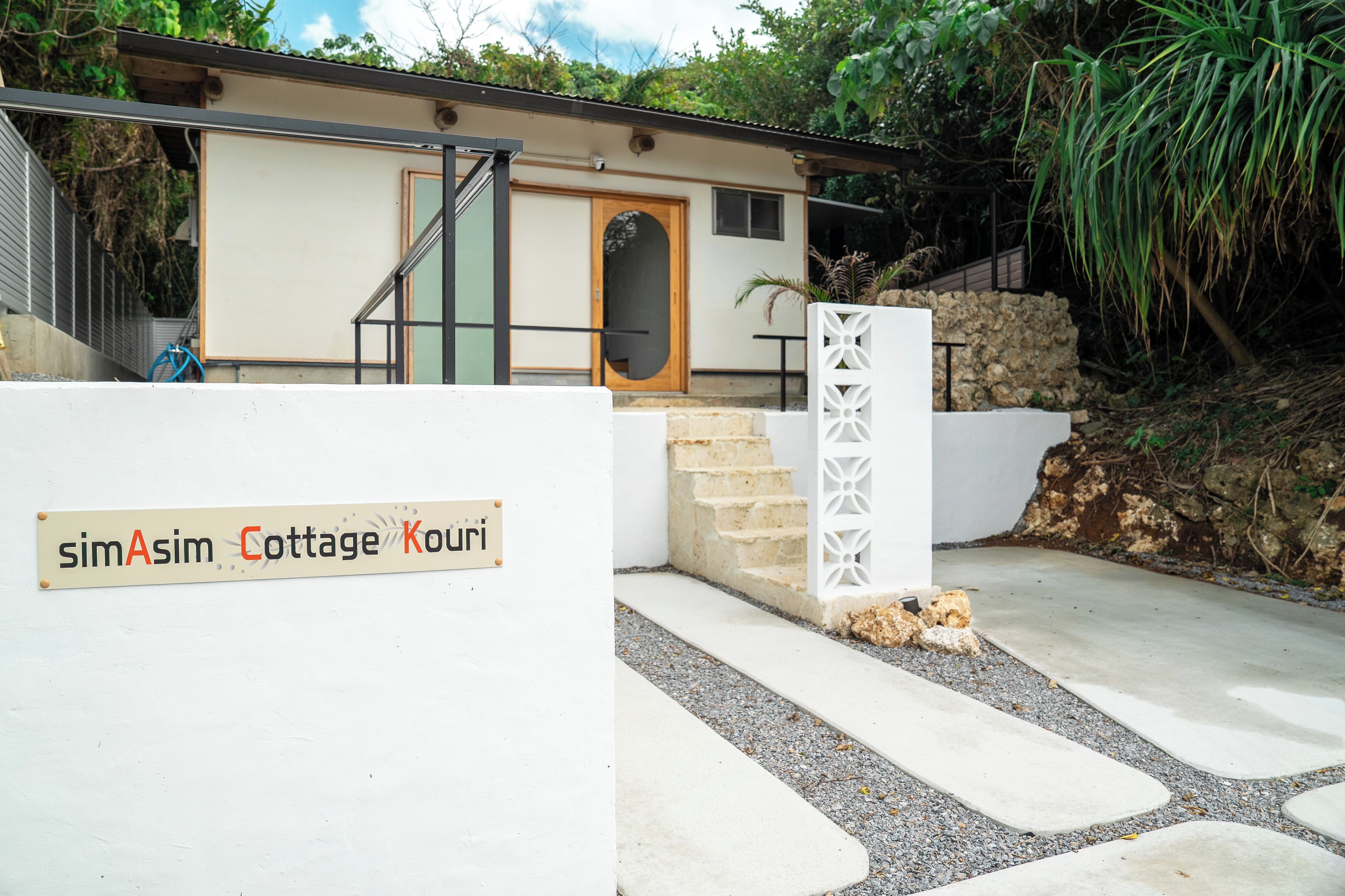 Señal de simAsim Cottage Kouri, con una casa moderna al fondo.