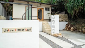 A sign for simAsim Cottage Kouri with a modern house in the background.