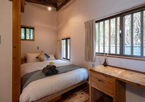 Un dormitorio con una cama, un escritorio de madera y un ventanal con cortinas.
