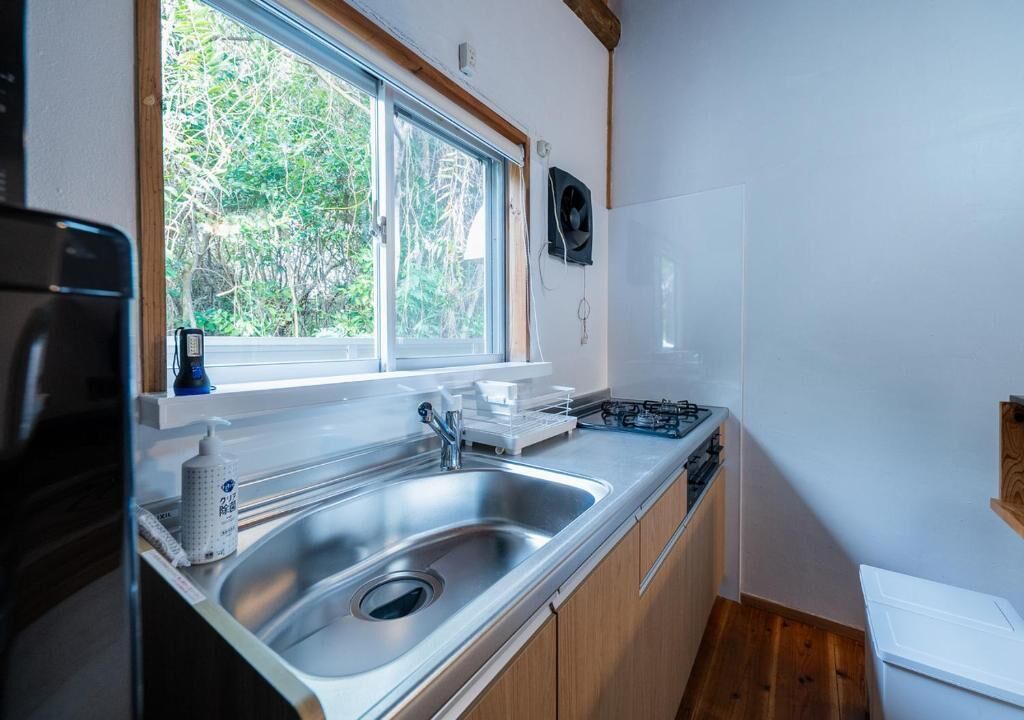 A compact kitchen with a sink, stove, and window overlooking greenery.