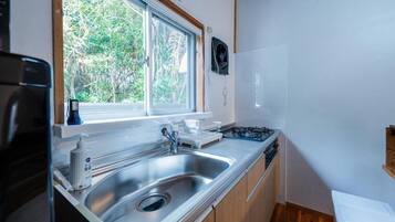 A compact kitchen with a sink, stove, and window overlooking greenery.