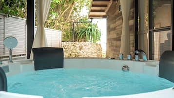 A hot tub with a stone wall and greenery in the background.