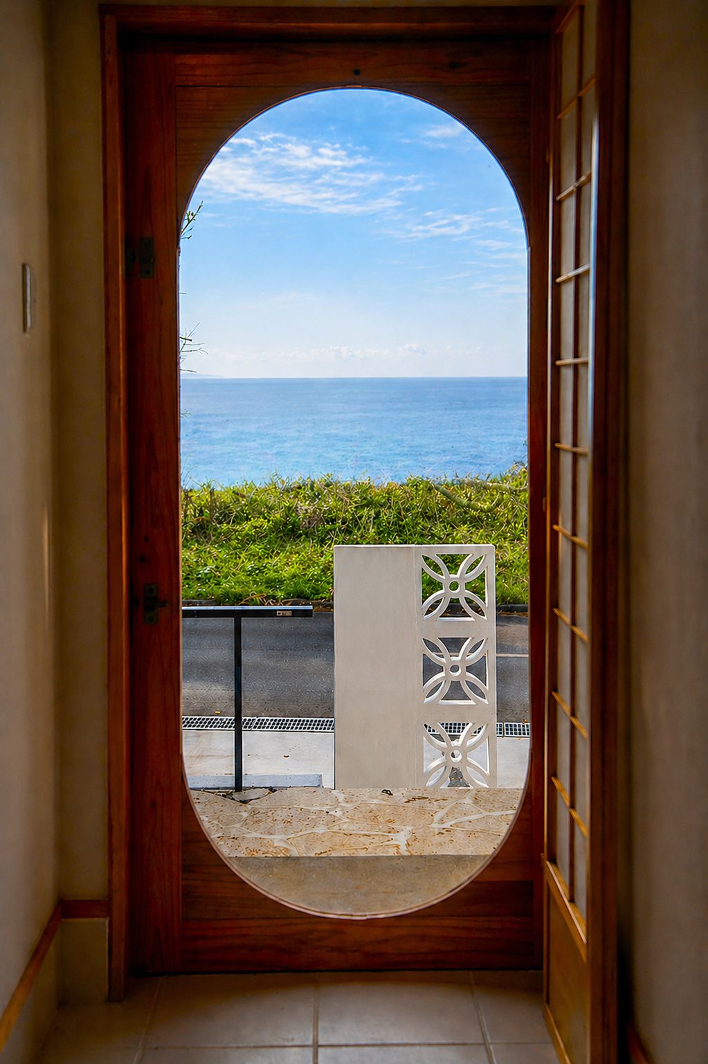 A doorway leading to a view of the sea with a wooden frame and a white decorative panel.