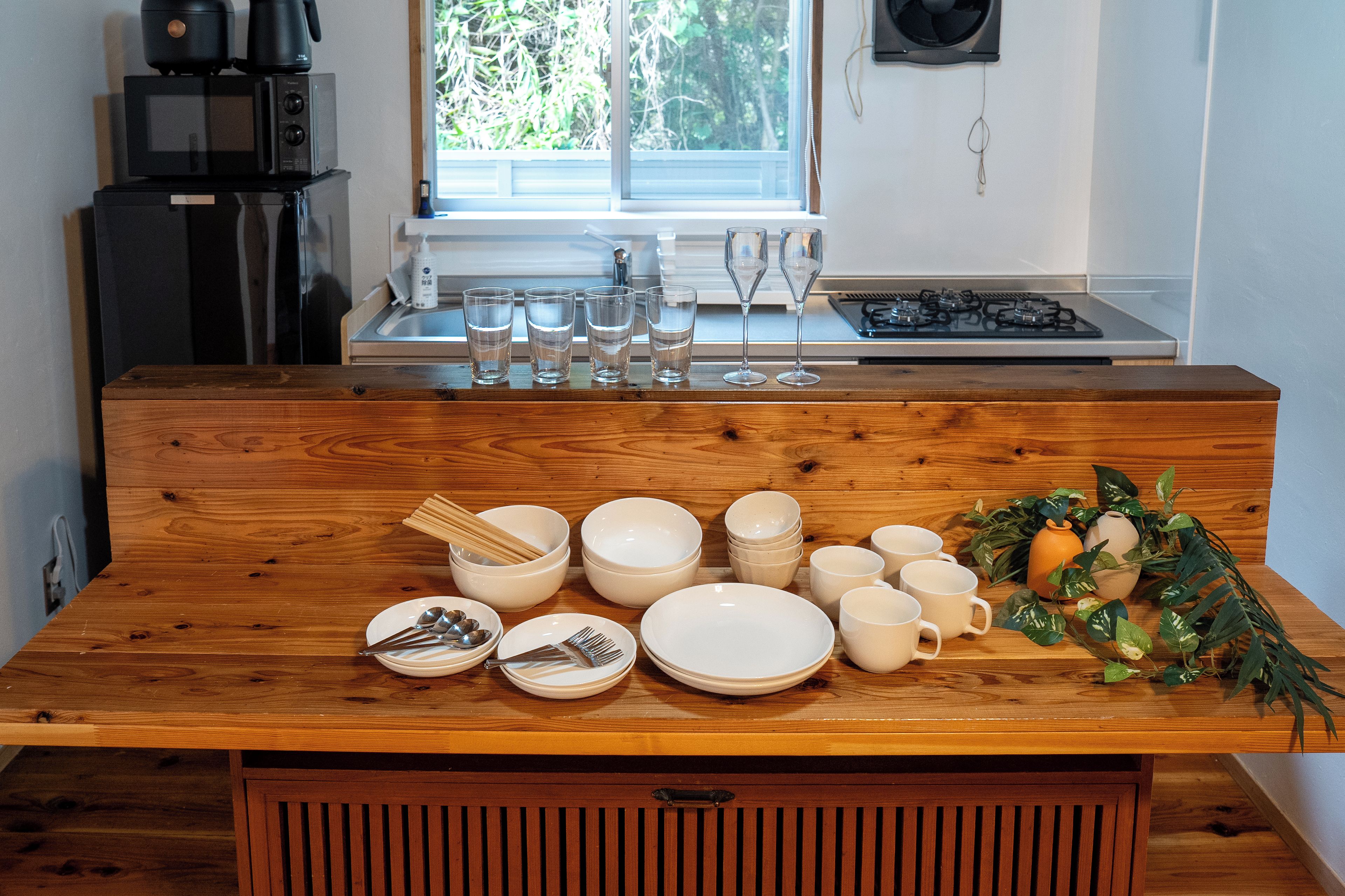 Una mesa de madera para comer con platos, tazones y cubiertos.
