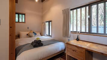 A bedroom with a bed, a desk, and a window with curtains.