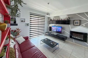 Una sala de estar moderna con un sofá rojo, una mesa de centro, un televisor de pantalla plana y una chimenea.