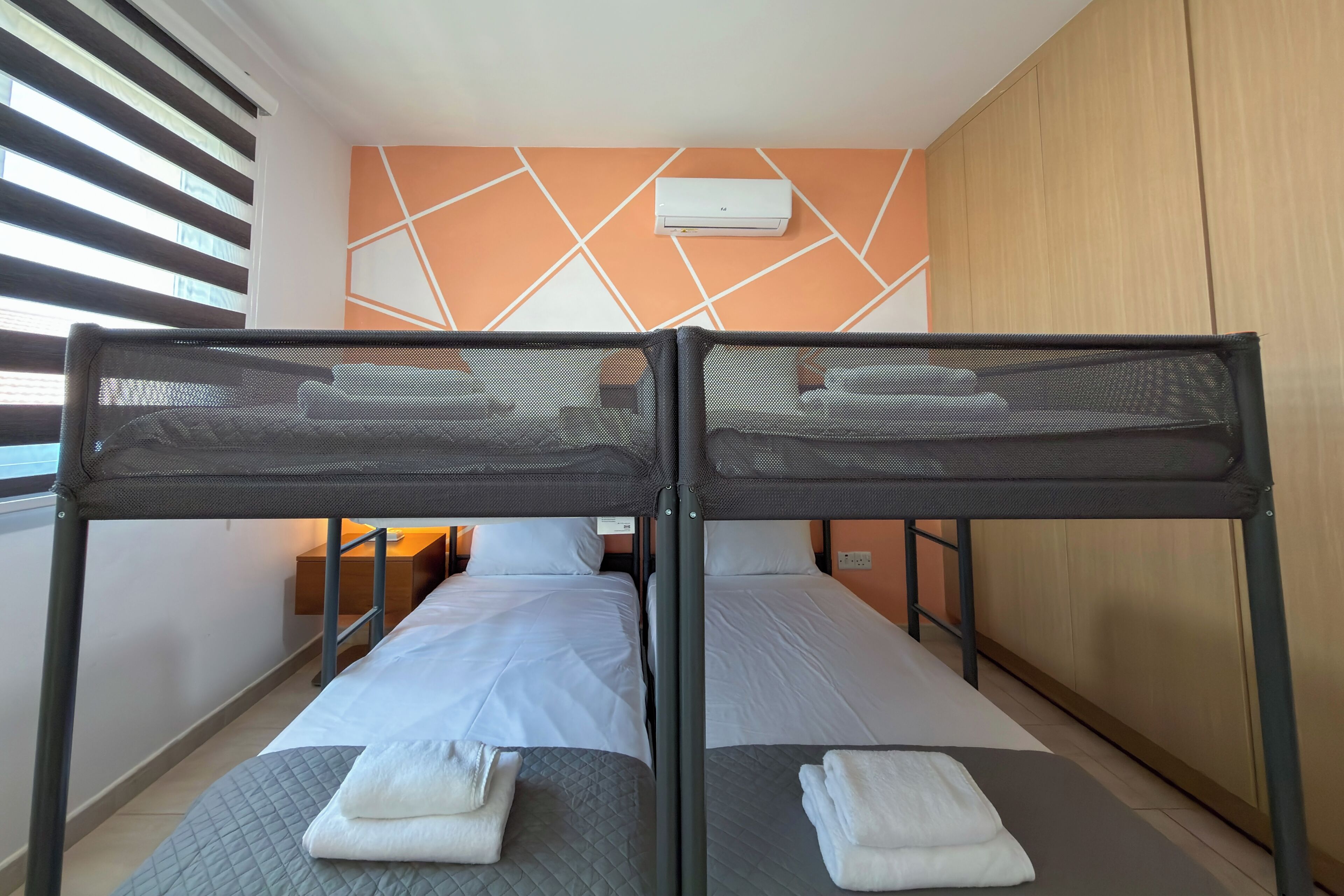 A twin room with two beds, a wardrobe, and a window with blinds.