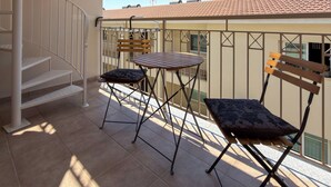 A balcony with a spiral staircase, a table, and two chairs. - Family Resort Apt with Pool Sleeps 6 (Paralimni)