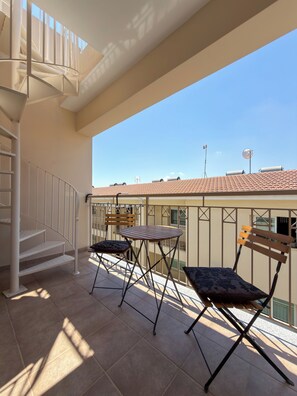 A balcony with a spiral staircase, a table, and two chairs. - Family Resort Apt with Pool Sleeps 6 (Paralimni)