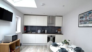 Een moderne keuken met witte kasten, een zwart aanrecht en een dakraam boven de eethoek.
