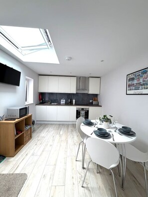 A modern kitchen with white cabinets, a black countertop, and a skylight above the dining area. - Modern Annexe, 10 Minutes from Oxford City Centre (Oxford)