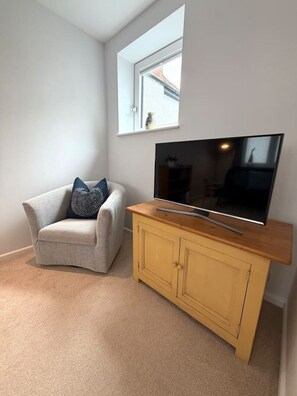 A living room with a sofa, a television on a wooden stand, and a window. - Modern Annexe, 10 Minutes from Oxford City Centre (Oxford)
