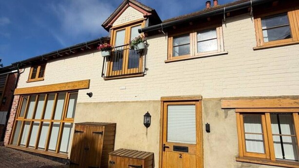 A two-story building with a balcony, a wooden door, and a brick entrance. - Market Place Retreat (Oxfordshire)