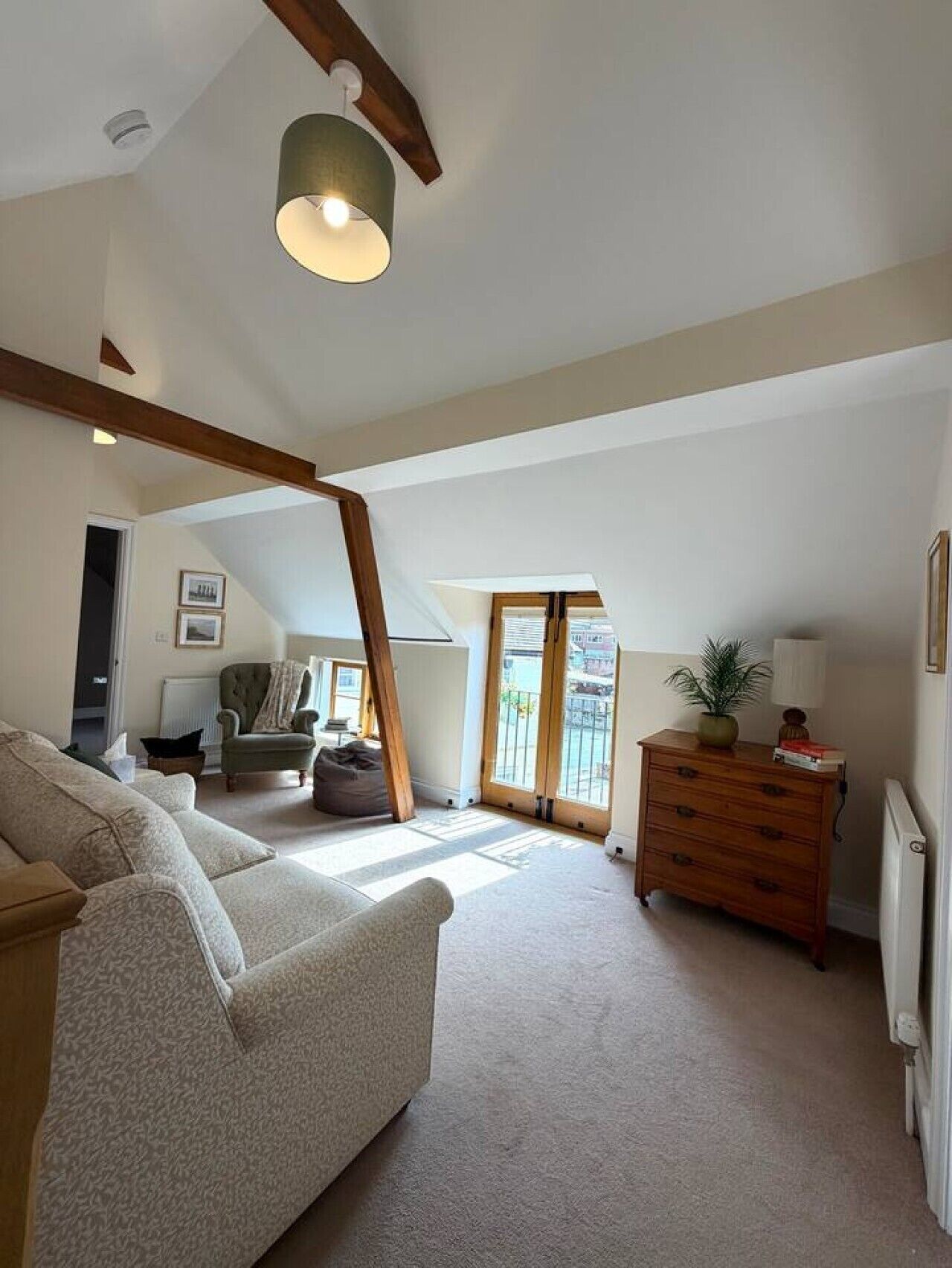 A spacious loft with a high ceiling, a large window, and a cozy seating area with a sofa and armchairs.