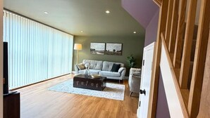 A spacious living area with a high ceiling, a sofa set, a coffee table, and a staircase with wooden railings. - Market Place Retreat (Oxfordshire)