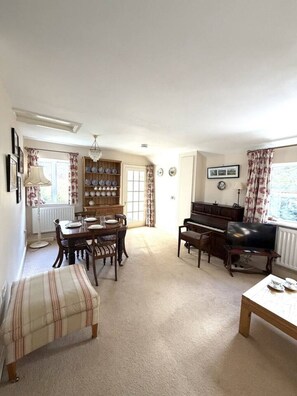 A living room with a dining area, a piano, and a television. - Charming Countryside Escape & Private Tennis Court (Denchworth)