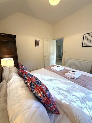 A hotel room with a bed, a bedside lamp, a door leading to a bathroom, and a framed picture on the wall. - Charming Countryside Escape & Private Tennis Court (Denchworth)