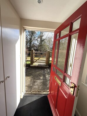 A red door leading to a covered outdoor area with a wooden gate. - Charming Countryside Escape & Private Tennis Court (Denchworth)