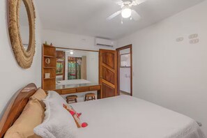 Ein Schlafzimmer mit einem Bett, einem Holzschrank, einem Spiegel und einem Deckenventilator.