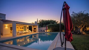 A swimming pool with lounge chairs and a covered area, surrounded by a well-maintained lawn and trees. - Villa Lara With Pool Walk To Sea (Medulin)