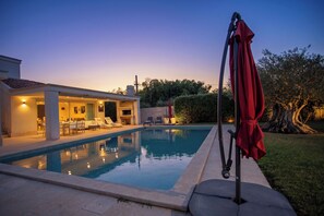 A swimming pool with lounge chairs and a covered area, surrounded by a well-maintained lawn and trees. - Villa Lara With Pool Walk To Sea (Medulin)