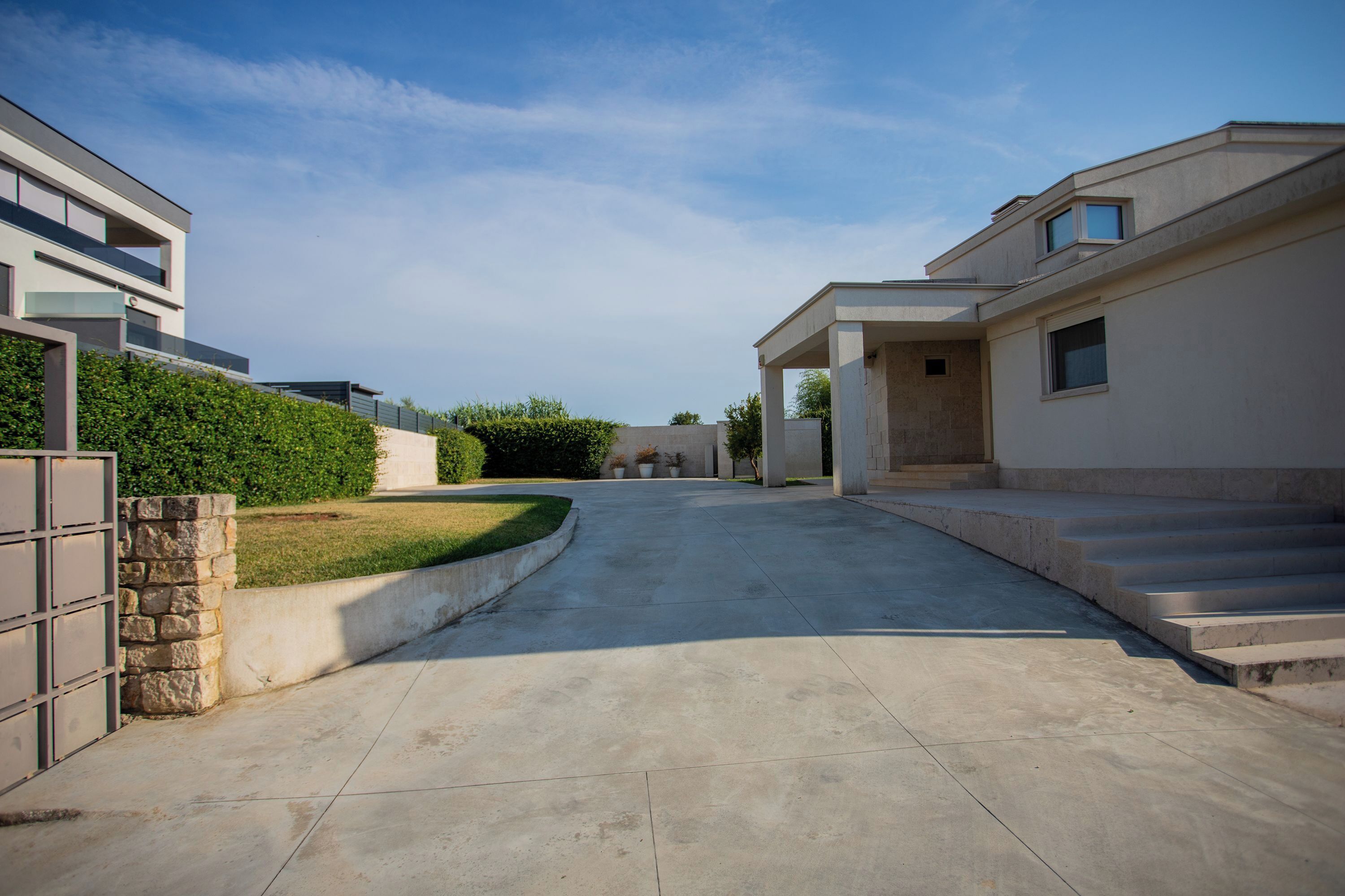 Una calle residencial con casas modernas, un camino de entrada pavimentado y cielo despejado.