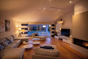 A modern living room with a fireplace, a television, and a pool view. - Villa Lara With Pool Walk To Sea (Medulin)