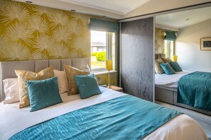Een hotelkamer met een groot bed, een spiegel en een raam met uitzicht op groen.