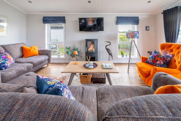 Een moderne woonkamer met een open haard, banken en een televisietoestel.