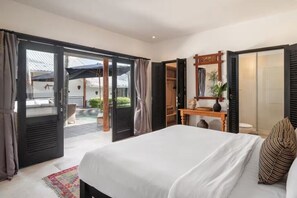 Ein Hotelzimmer mit Bett, Schreibtisch und einer Glastür zum Außenbereich.