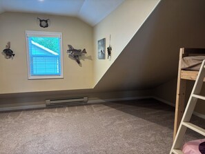 Una habitación con literas, una ventana con persianas y adornos en la pared, incluyendo peces y un cráneo.