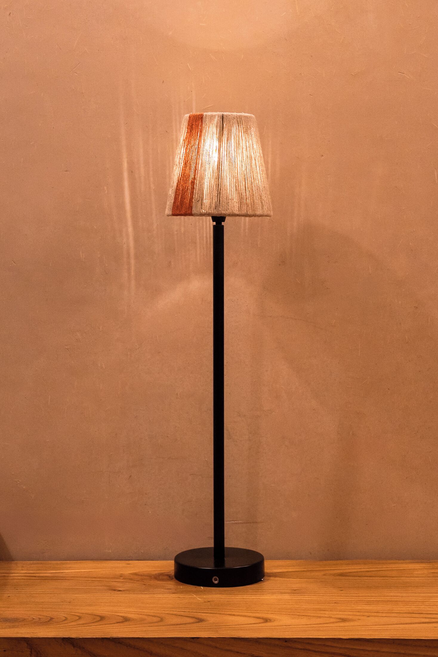 A floor lamp with a textured lampshade on a wooden surface.