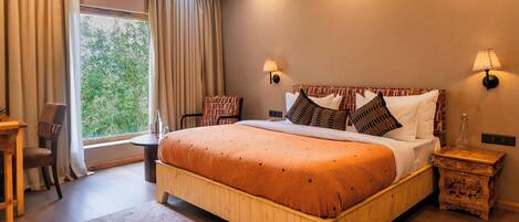 A bedroom with a large bed, a wooden nightstand, a desk, and a chair.