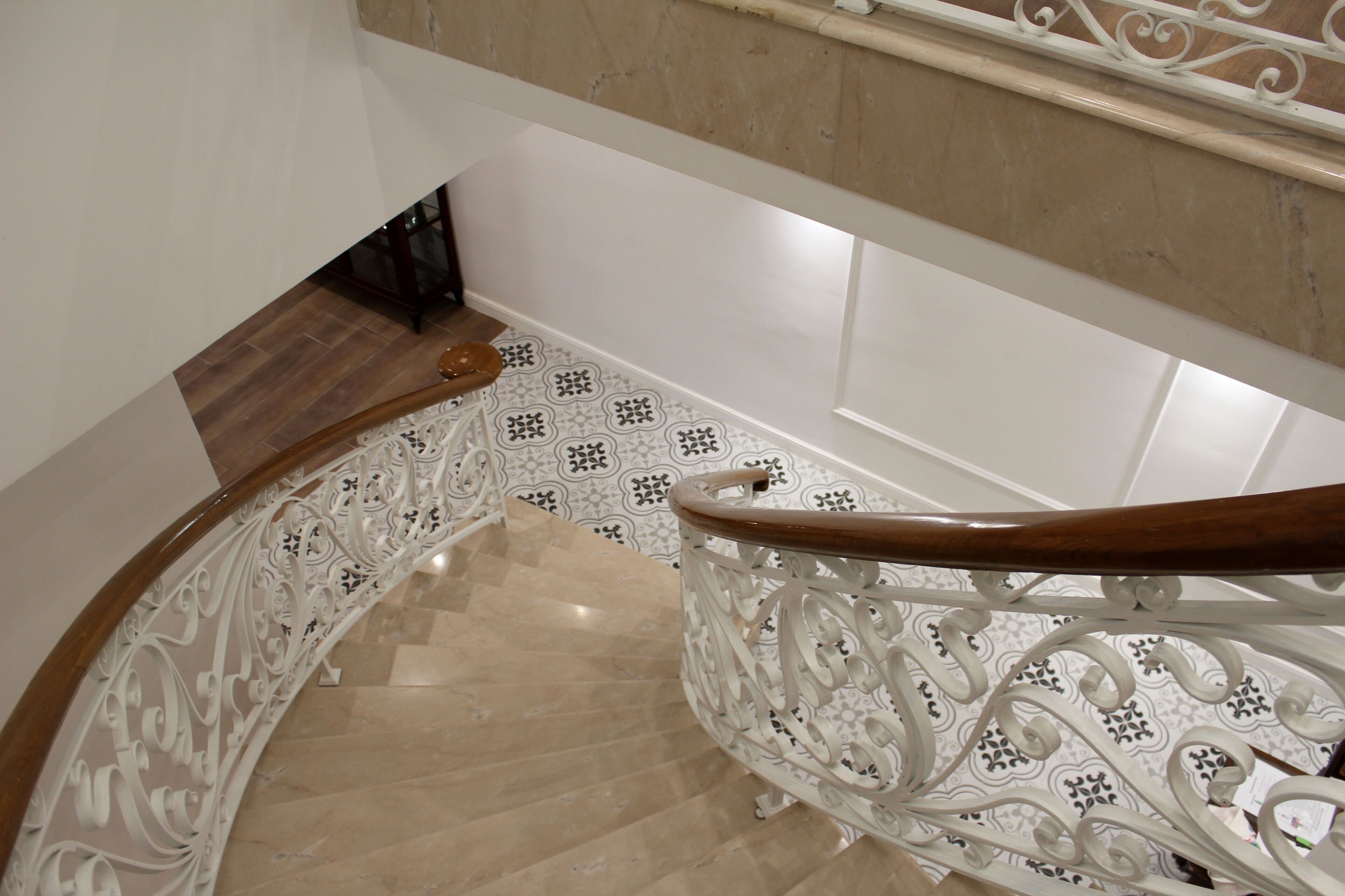 A curved staircase with ornate white railings and a wooden handrail.