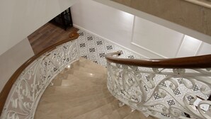 A curved staircase with ornate white railings and a wooden handrail.