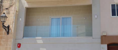 Un edificio de varios pisos con balcones, ventanas amplias y una entrada a nivel de calle con puerta de vidrio.