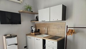 A modern kitchen with white cabinets, a wooden countertop, a sink, and a black stove. - Seven Lakes ApartHotel RTA (Burolo)