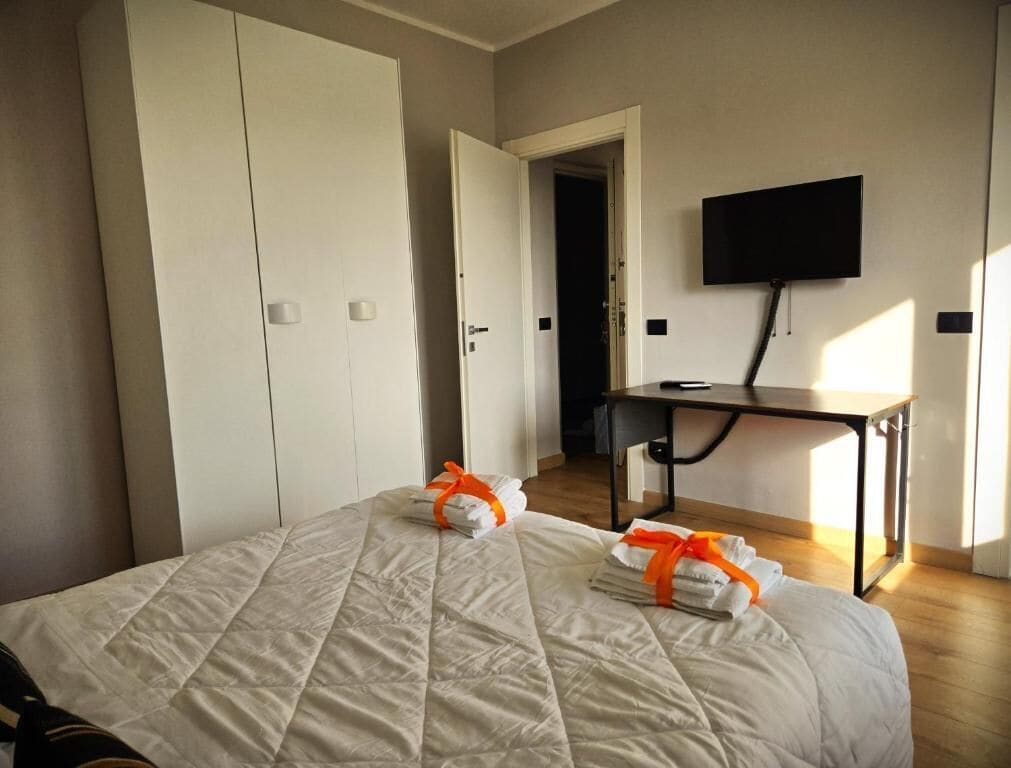 A hotel room with a bed, a desk, a TV, and a wardrobe.