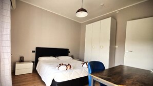 A bedroom with a bed, bedside table, wardrobe, and a dining table. - Seven Lakes ApartHotel RTA (Burolo)